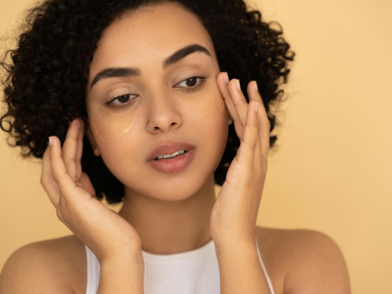A lady applying vitamin E oil under her eyes to avoid puffiness